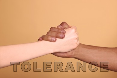 Tolerance, support and cooperation concept. People of different races clasping hands on light brown background, closeup