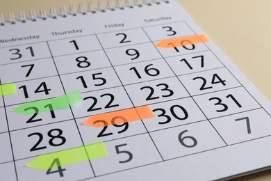 Photo of Timetable. Calendar page with colorful sticky notes on beige background, closeup