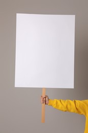 Woman holding blank sign on light grey background, closeup. Space for design