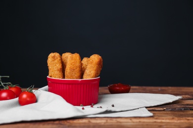 Bowl of cheese sticks on table against black background. Space for text