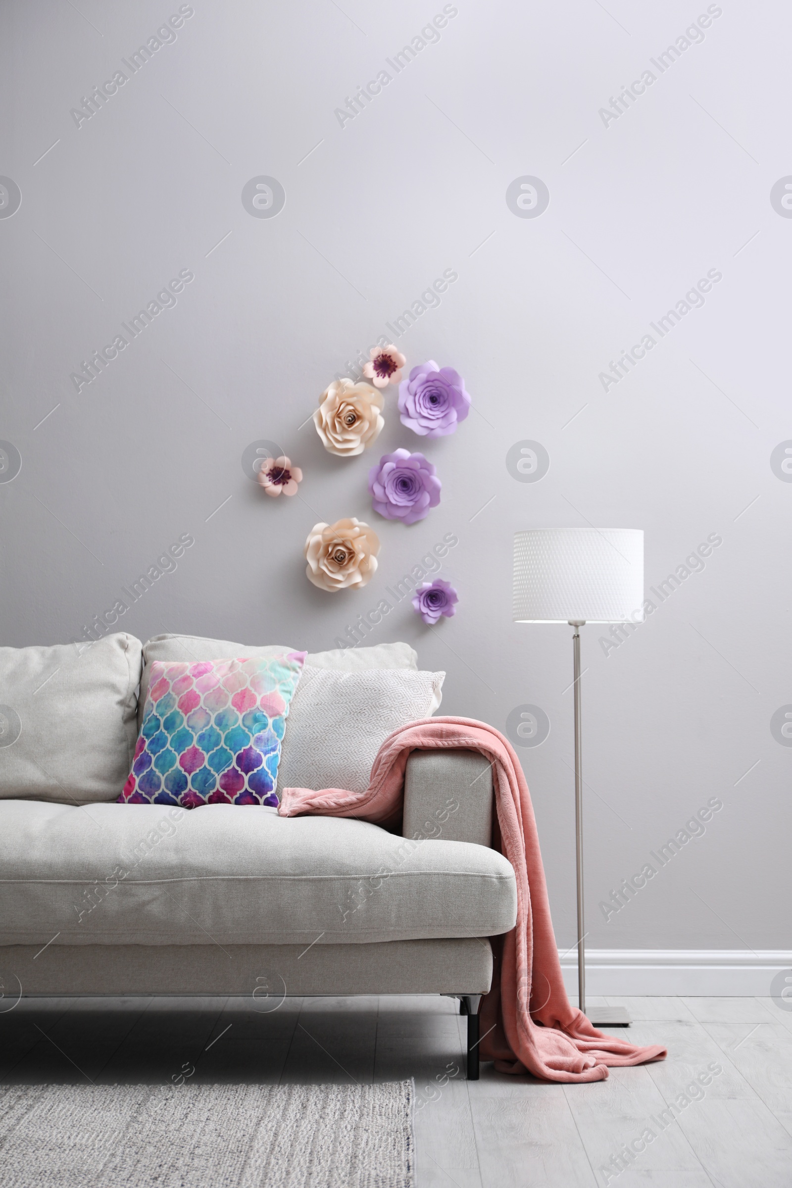 Photo of Comfortable sofa near wall with floral decor in living room