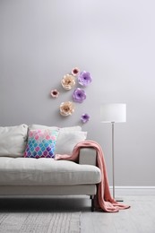 Comfortable sofa near wall with floral decor in living room