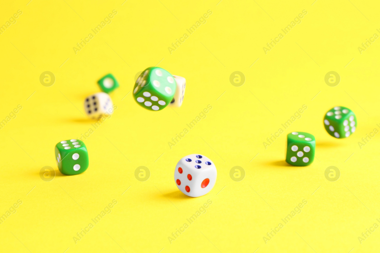 Photo of Many color game dices falling on yellow background