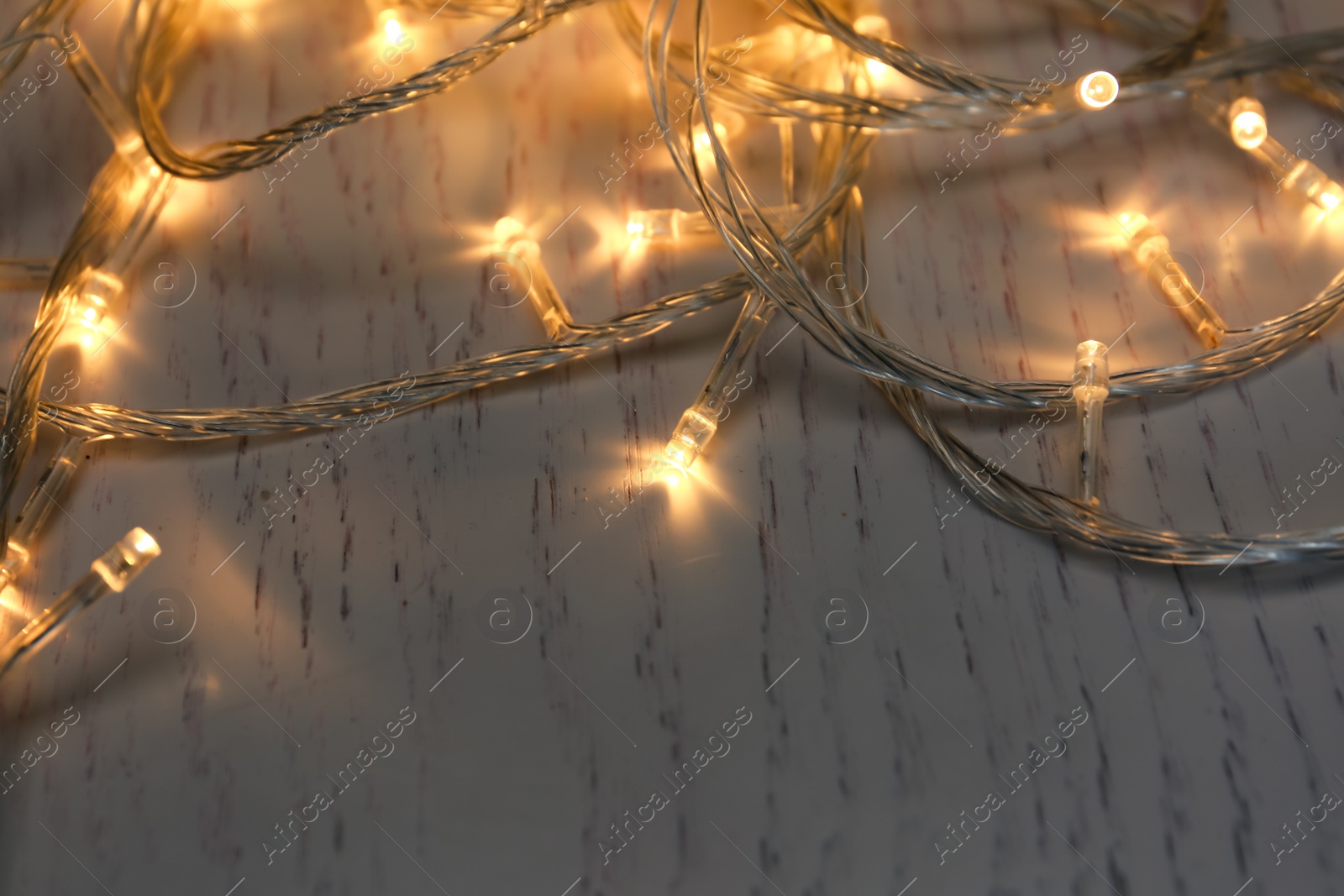 Photo of Glowing Christmas lights on white wooden background