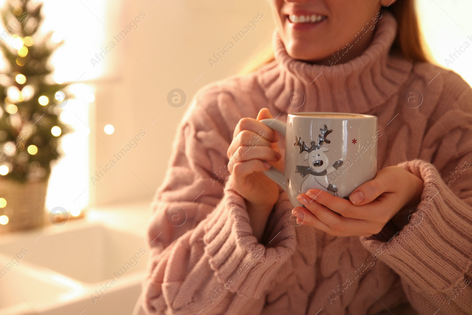 Photo of Woman holding cup with hot drink in kitchen, closeup