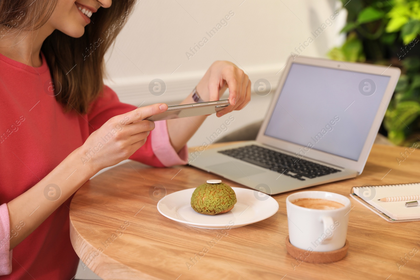 Photo of Young blogger taking photo of dessert at table in cafe, closeup