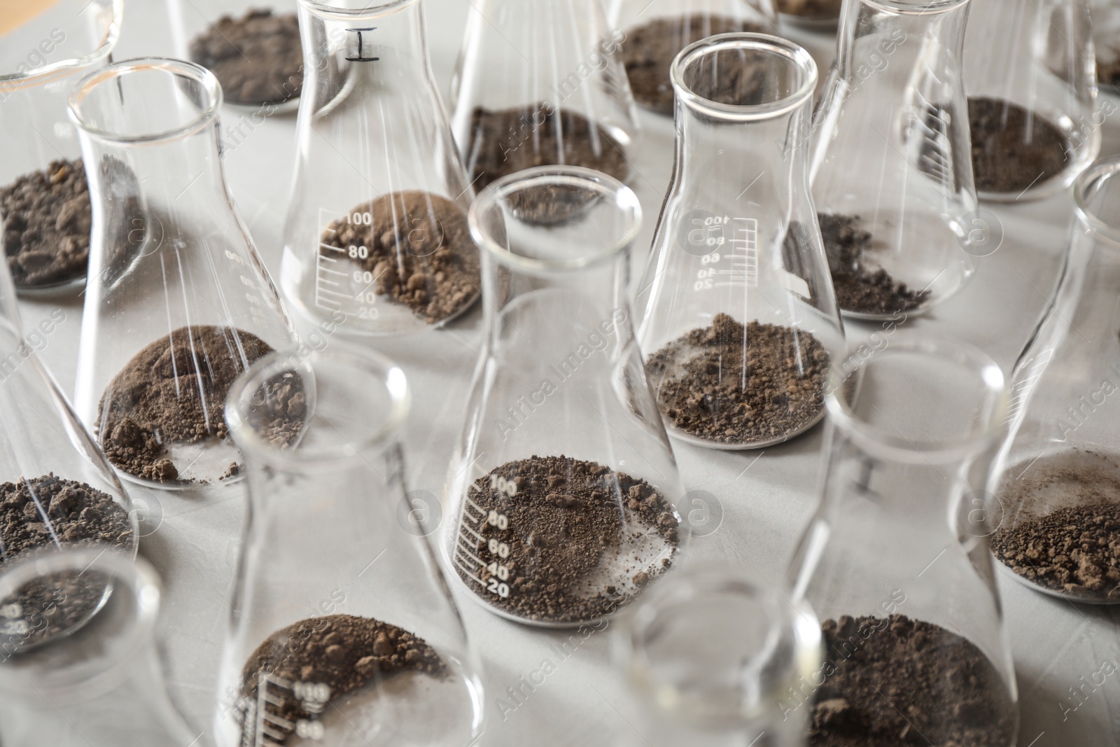 Photo of Glassware with soil samples on grey table. Laboratory research