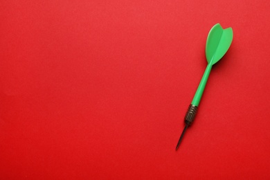 Photo of Green dart arrow on red background, top view with space for text