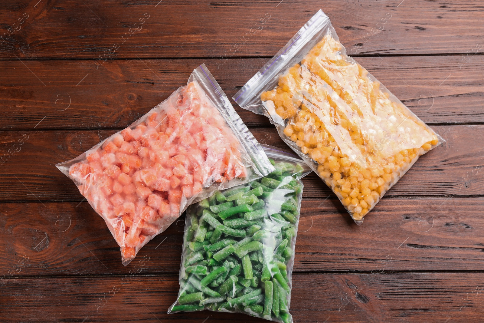 Photo of Different frozen vegetables on wooden table, flat lay