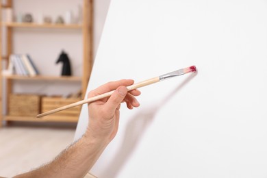 Photo of Man painting on canvas in studio, closeup