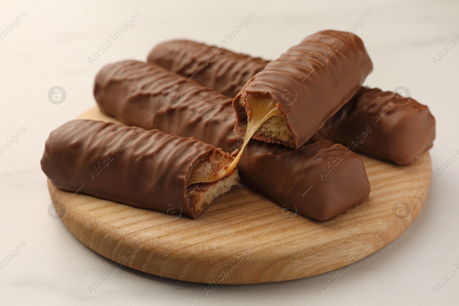 Photo of Sweet tasty chocolate bars with caramel on white table, closeup