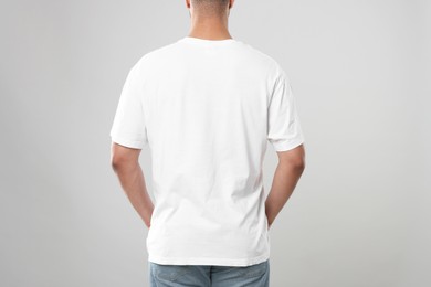 Man wearing white t-shirt on gray background, closeup