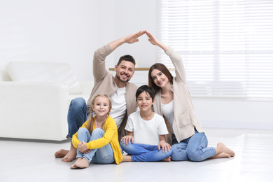 Photo of Happy family forming house roof with their hands at home. Insurance concept