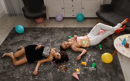 Photo of Drunk friends sleeping on floor in messy room after party