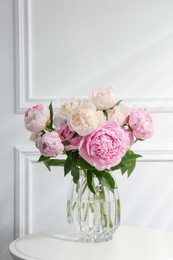 Bouquet of beautiful peonies in glass vase on white table