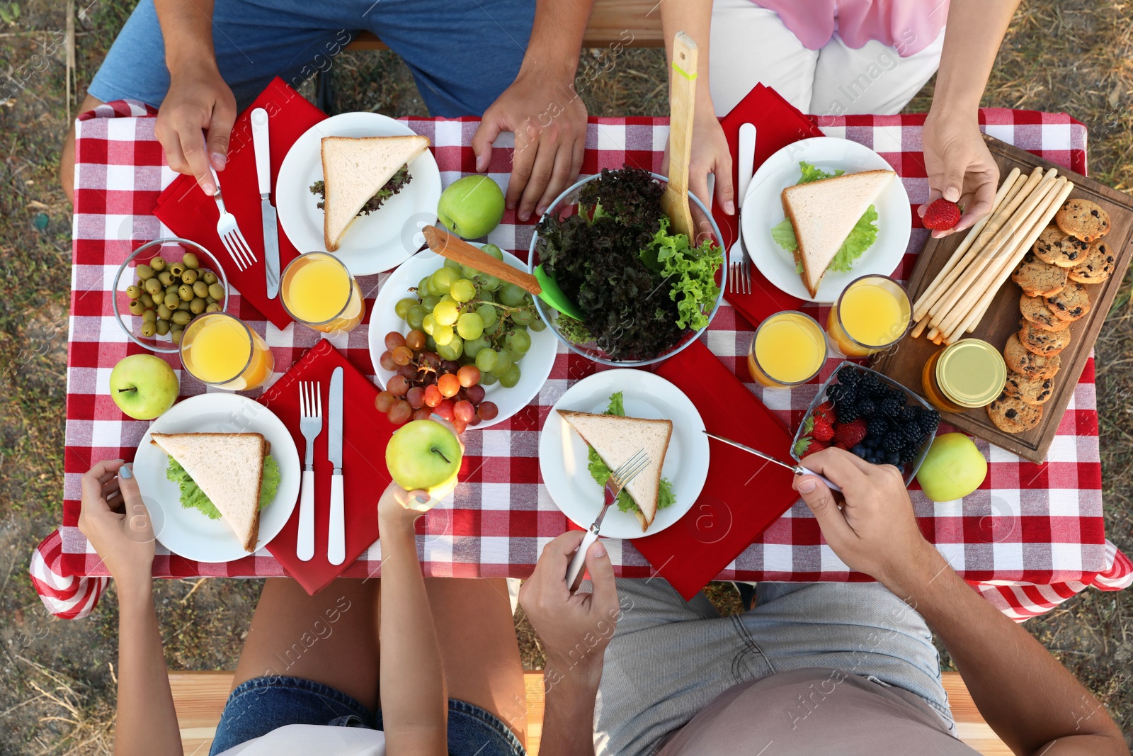 Photo of Young people having picnic at table in park, top view