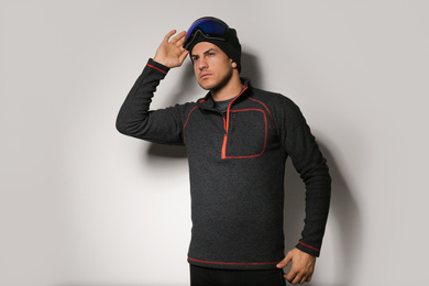 Photo of Man wearing fleece jacket and goggles on light grey background. Winter sport clothes