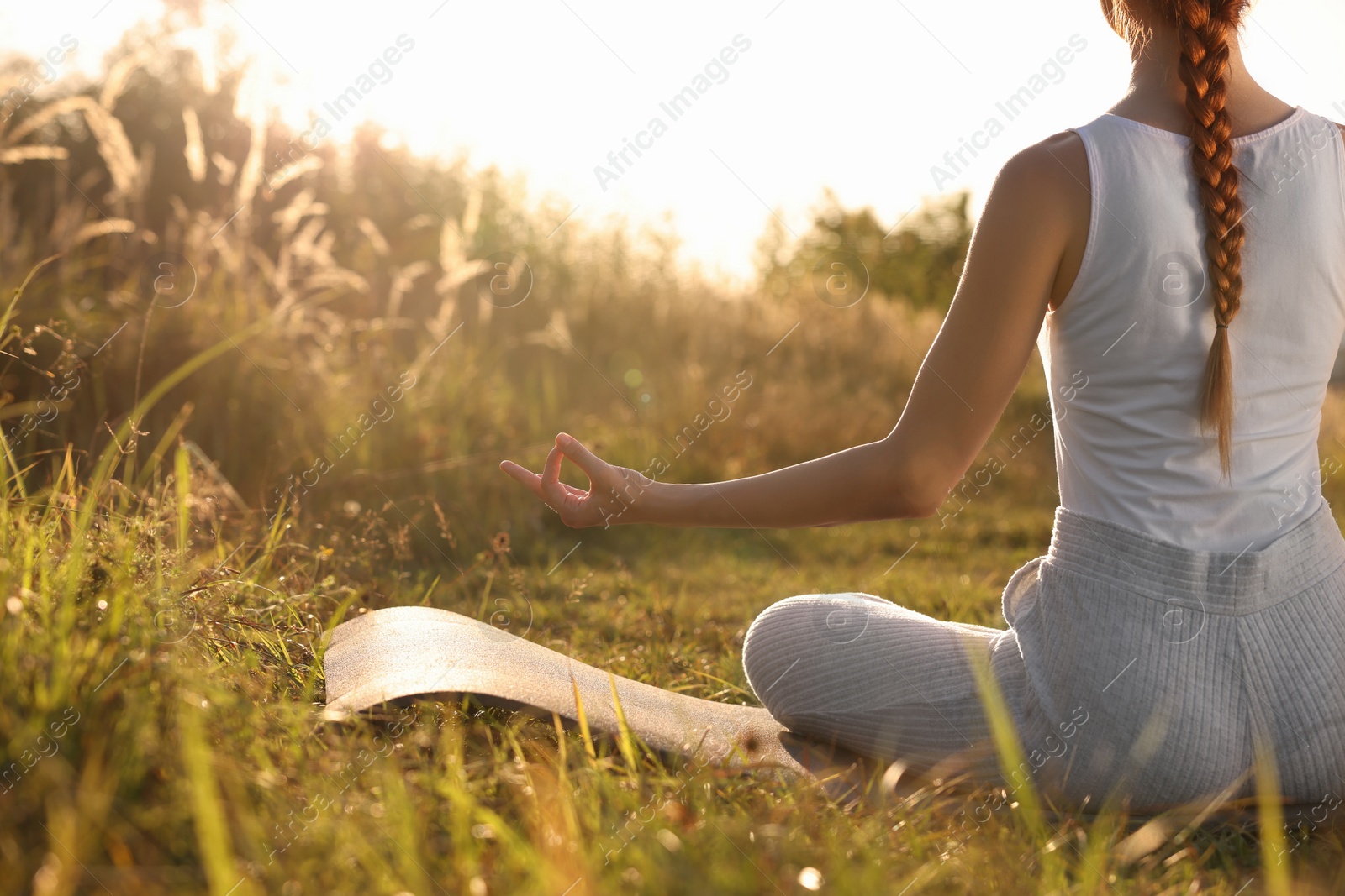 Photo of Woman practicing Padmasana on yoga mat outdoors, closeup with space for text. Lotus pose
