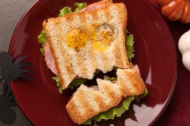 Photo of Cute monster sandwich with fried eggs served on grey textured table, flat lay. Halloween snack