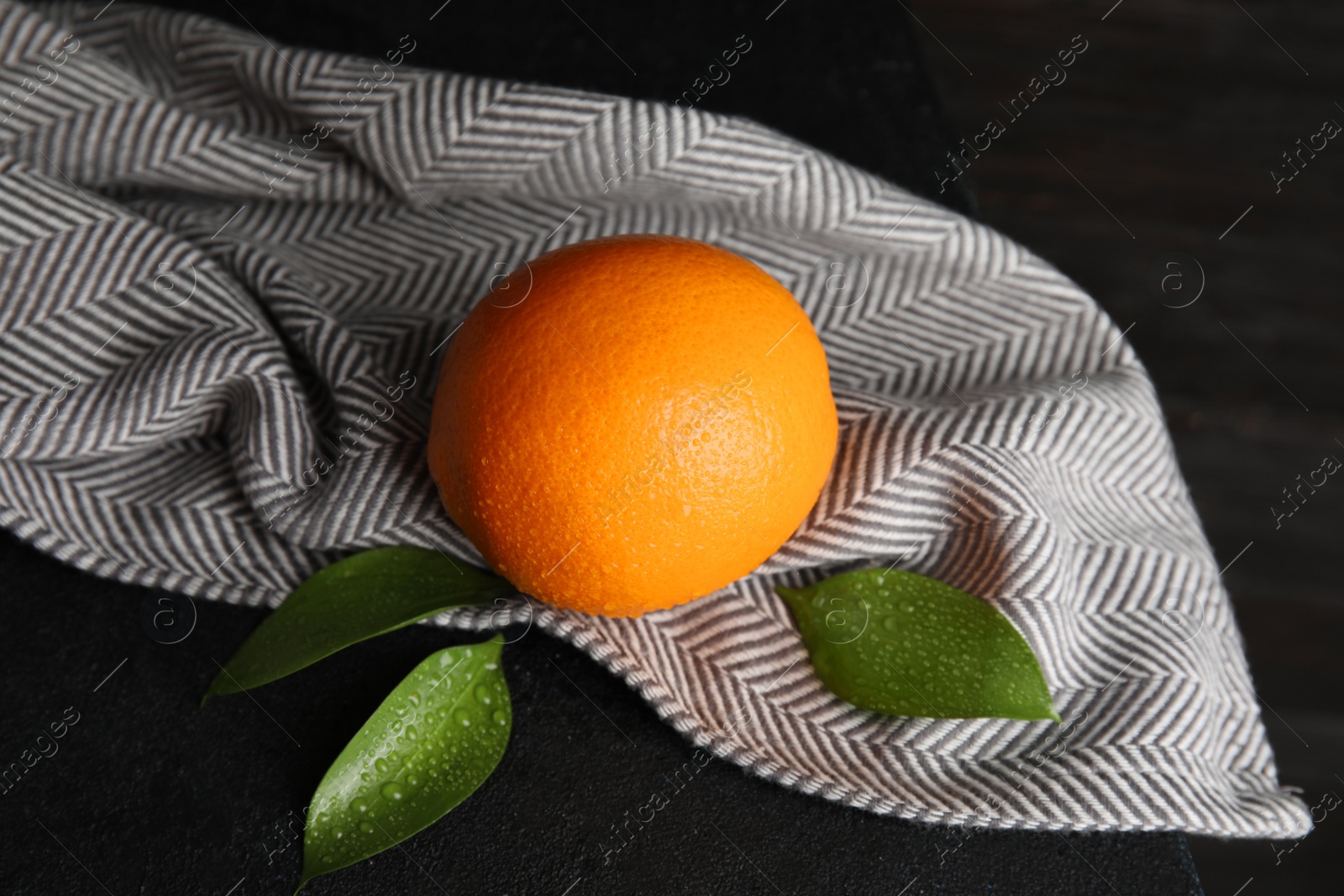 Photo of Fresh orange with leaves and napkin on table