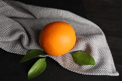 Fresh orange with leaves and napkin on table