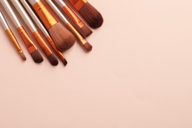 Photo of Set of makeup brushes on beige background, flat lay. Space for text