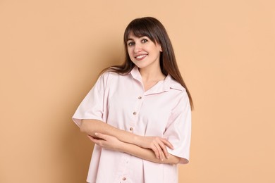 Photo of Happy woman wearing pyjama on beige background