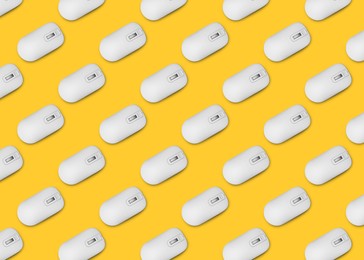 Image of Many white computer mouses on yellow background, flat lay. Seamless pattern design