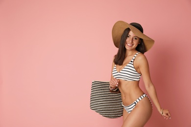 Photo of Pretty sexy woman with slim body in stylish striped bikini on coral background, space for text