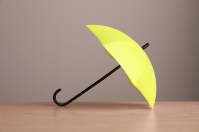 Small yellow umbrella on wooden table against beige background