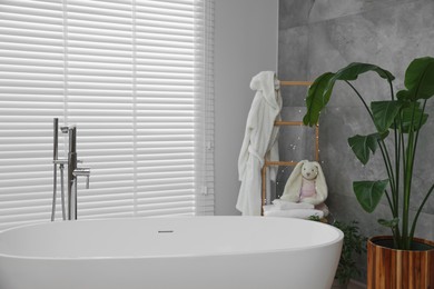 Stylish bathroom interior with beautiful tub and potted plant
