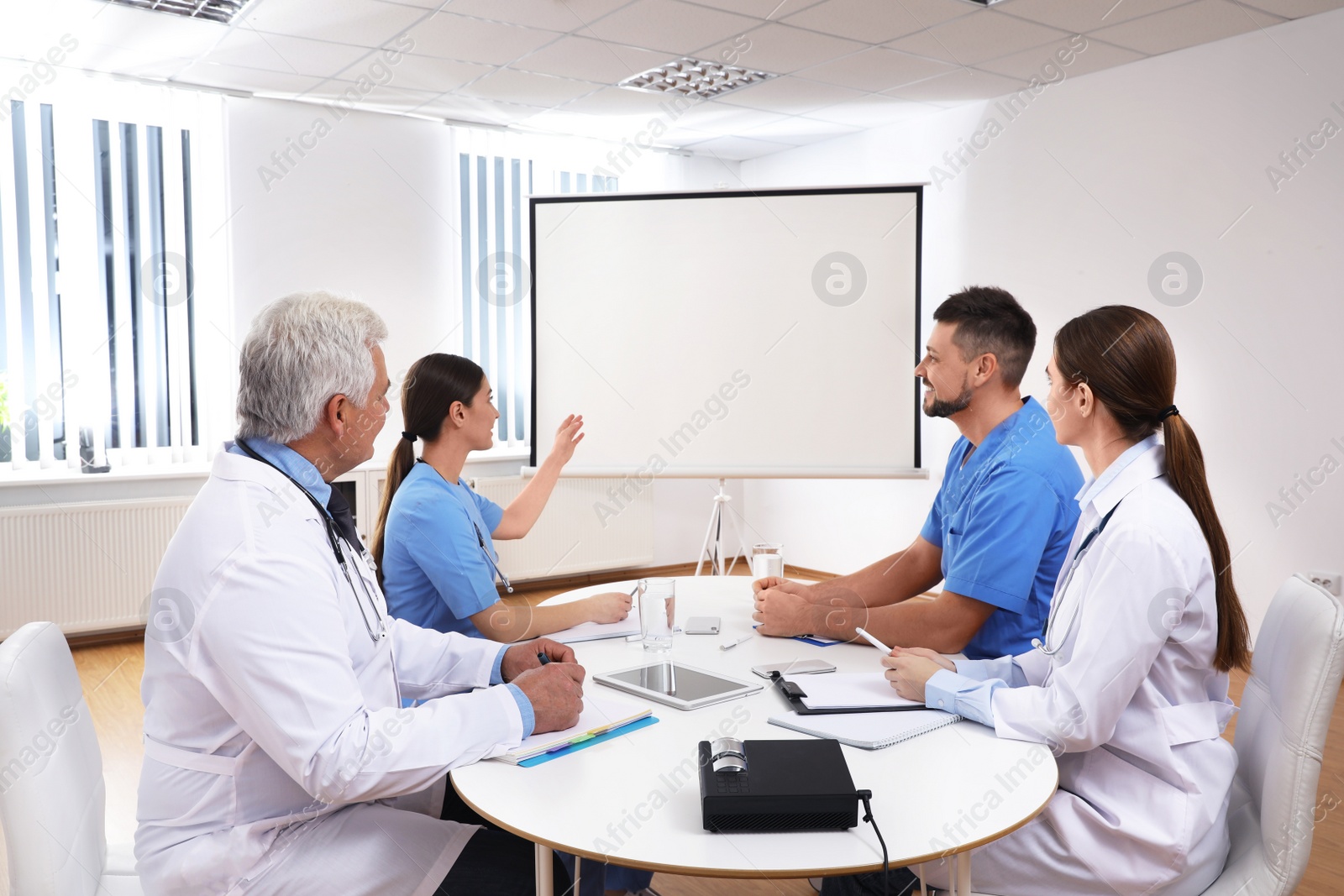 Photo of Team of doctors using video projector during conference indoors