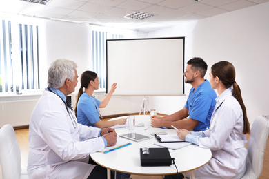 Team of doctors using video projector during conference indoors