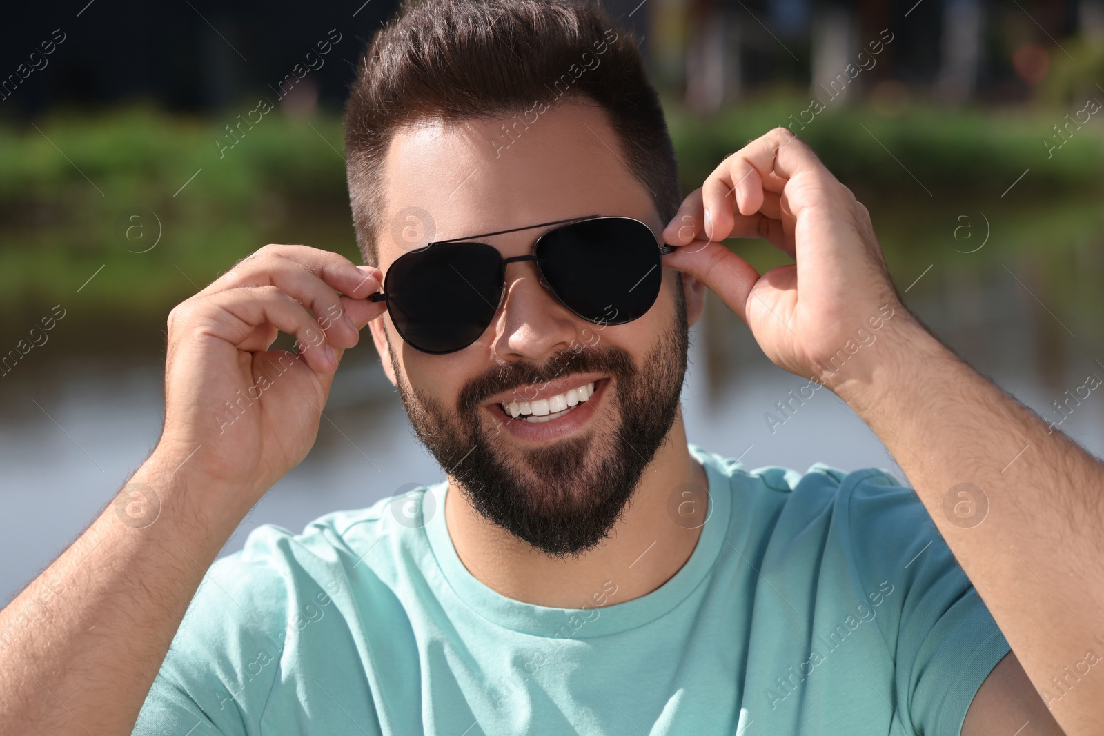 Photo of Handsome smiling man in sunglasses near river