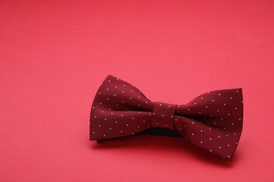 Photo of Stylish burgundy bow tie on red background, space for text