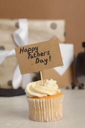 Happy Father's Day. Tasty cupcake with greetings on light table, closeup