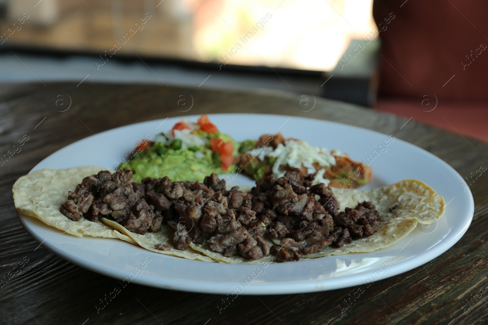 Photo of Plate with delicious tacos served on wooden table