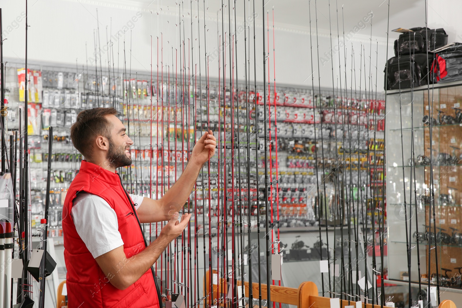 Photo of Salesman with fishing rods in sports shop. Space for text