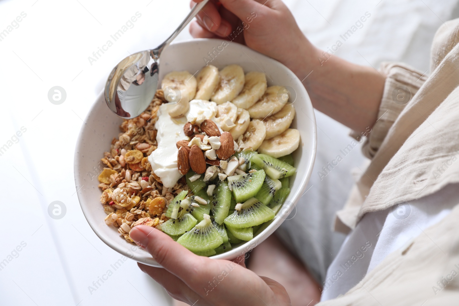 Photo of Woman eating tasty granola indoors, closeup view