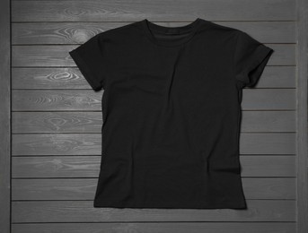 Stylish black T-shirt on gray wooden table, top view