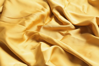 Photo of Pale orange shiny fabric as background, closeup view