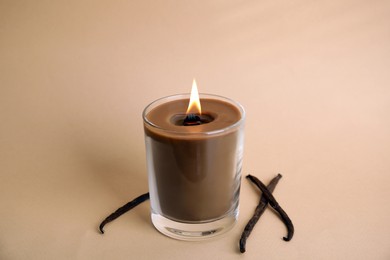 Photo of Beautiful candle with wooden wick and vanilla sticks on beige background