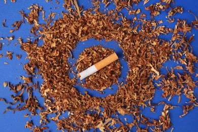 Photo of Cigarette with prohibition sign made of dry tobacco on blue background, flat lay. Quitting smoking concept