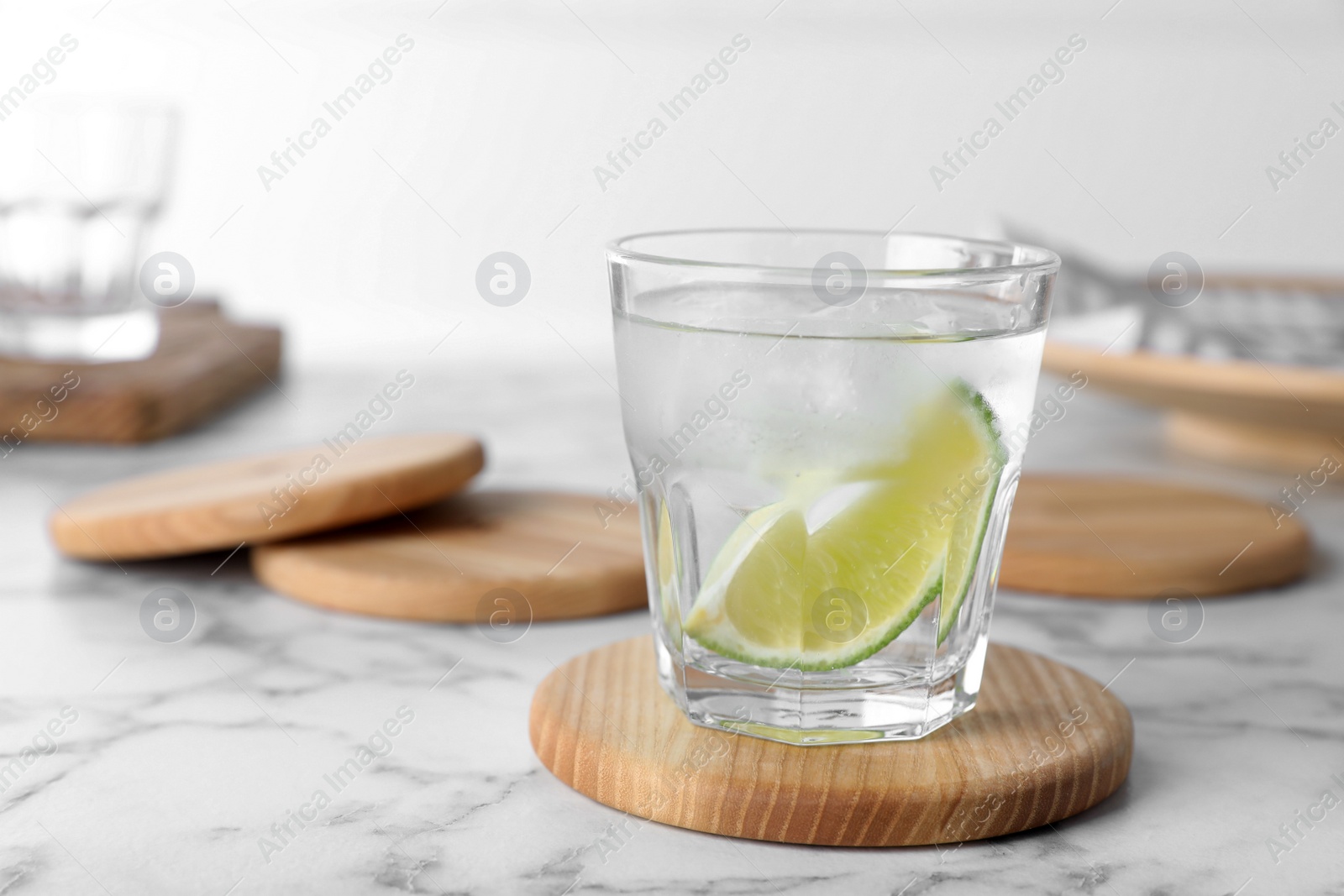 Photo of Glass of lemonade with stylish cup coasters on marble table at white backstage, space for text