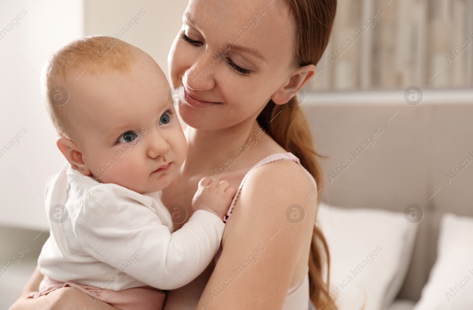 Photo of Young woman with her little baby resting after breast feeding in bedroom