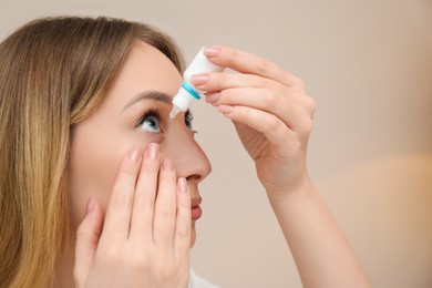 Photo of Young woman using eye drops on beige background