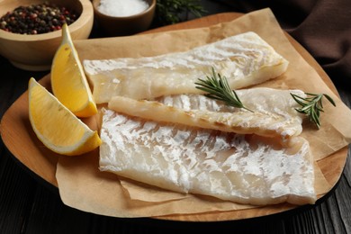 Photo of Fresh raw cod fillets, spices and lemon on wooden table, closeup