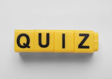 Photo of Yellow cubes with word Quiz on white background, top view
