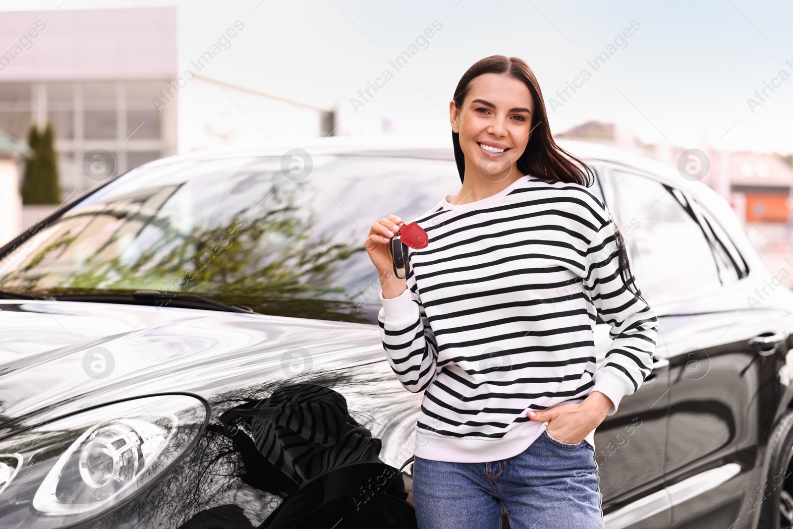 Photo of Woman holding car flip key near her vehicle outdoors