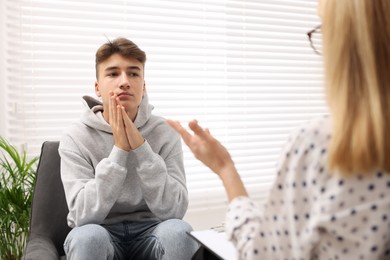 Psychologist working with teenage boy in office